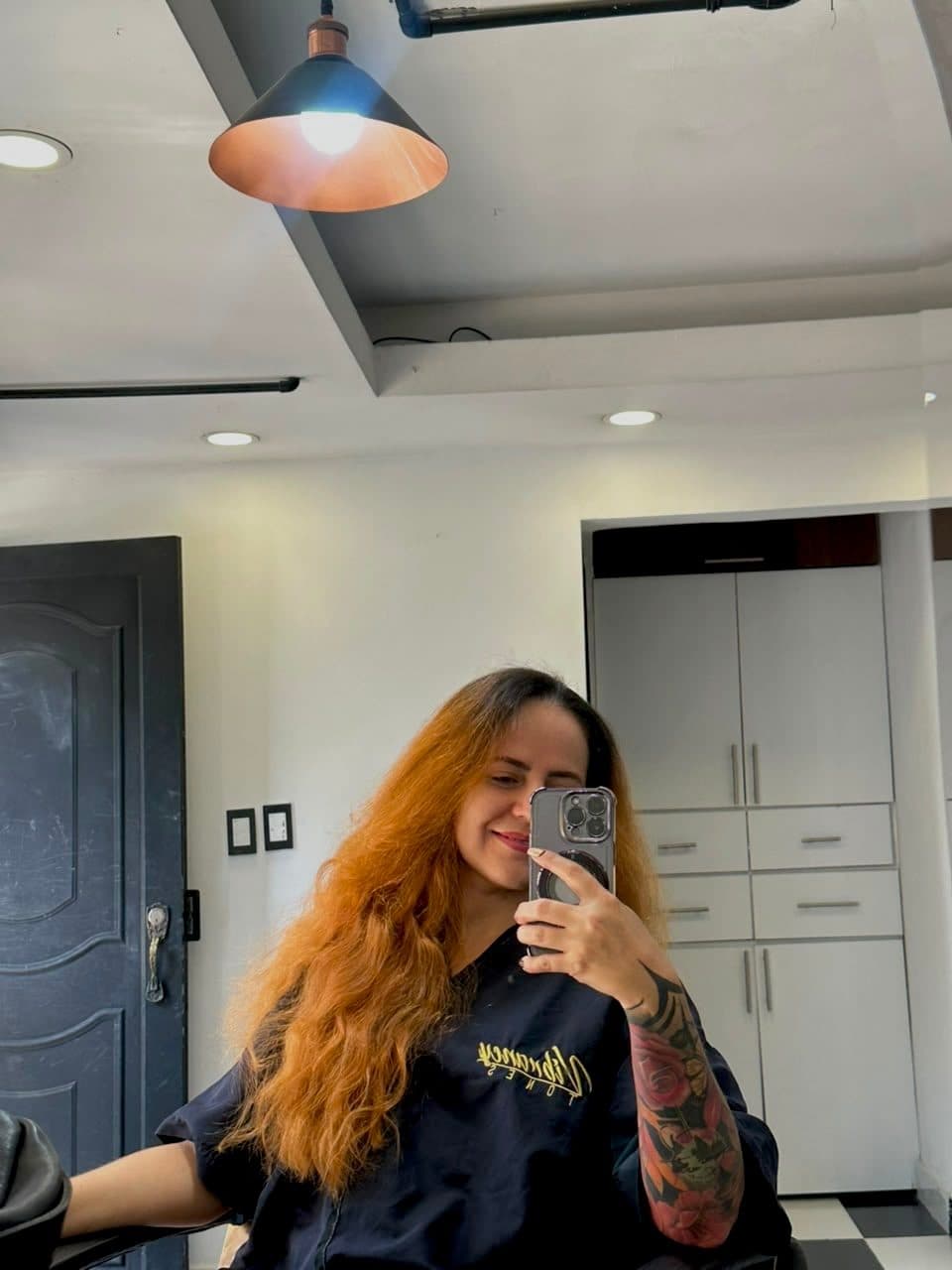 Antes: cabello largo cobrizo, frente al espejo del salón.