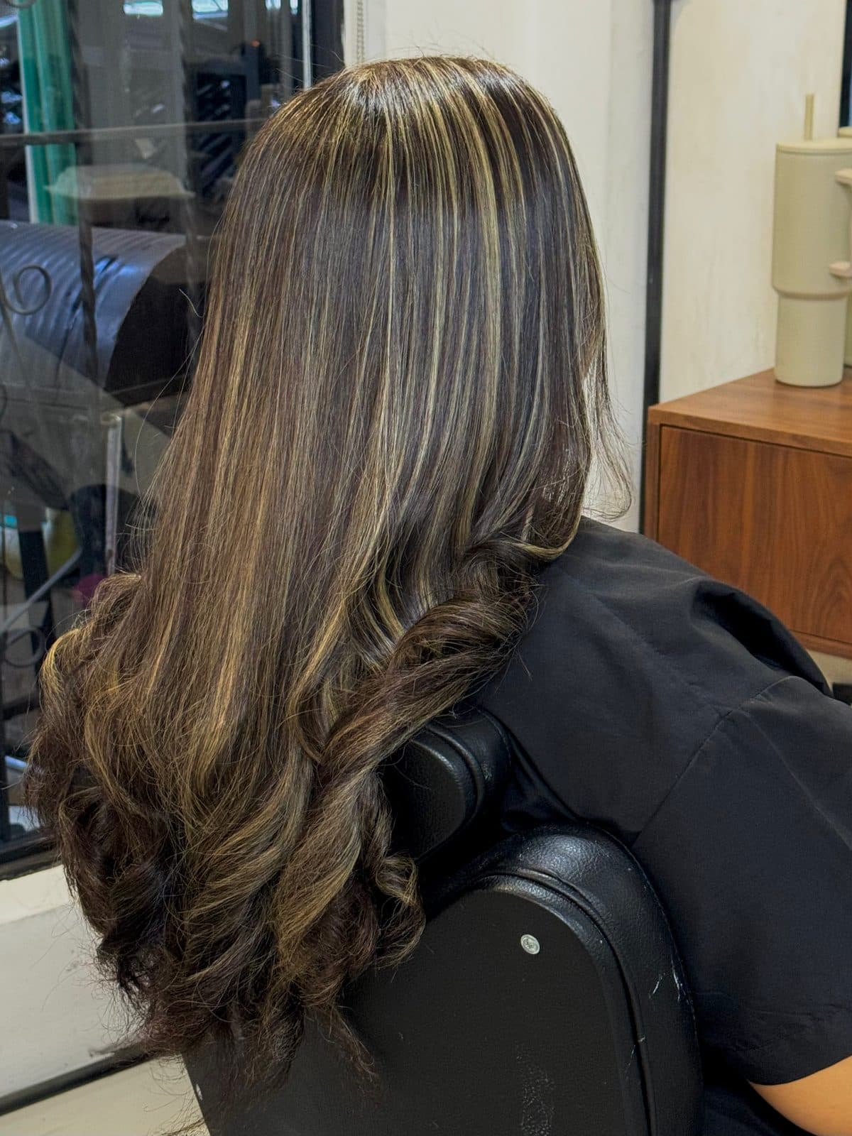 Cabello oscuro con mechas claras y ondas en las puntas, visto de espaldas.