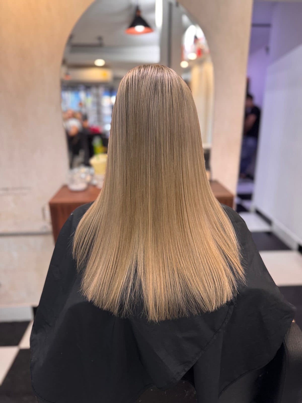 Cabello rubio beige, liso, visto de espaldas en el salón.